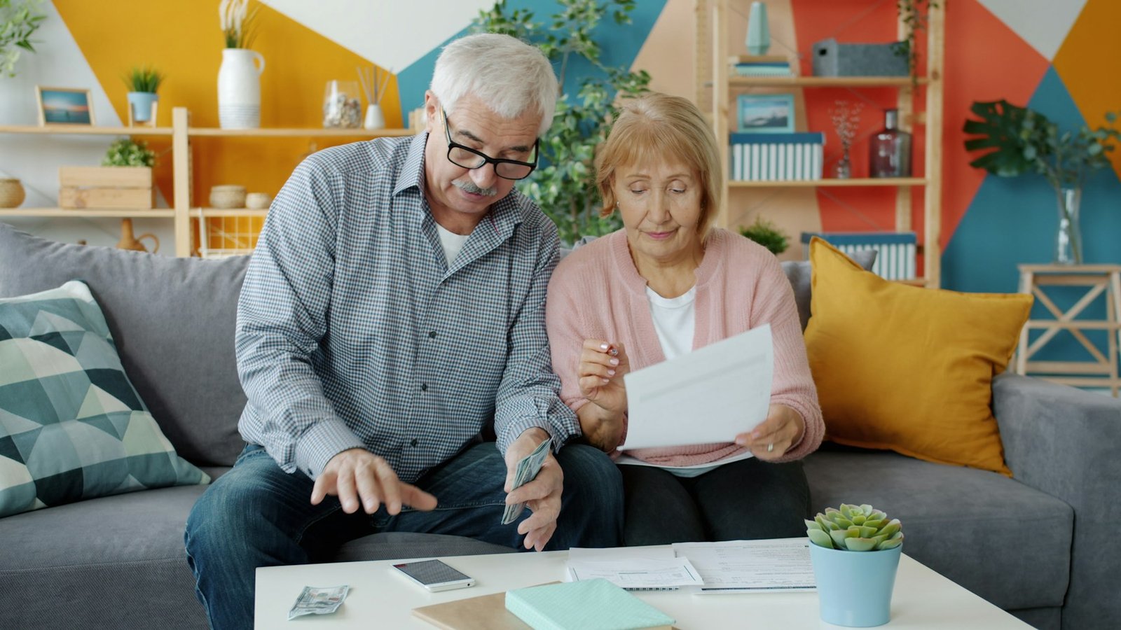 Senior couple in their seventies reviewing life insurance paperwork together at home